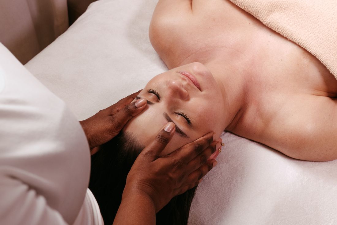 Maos do terapeuta apoiando a cabeca e o rosto da paciente durante sessao de terapia manual