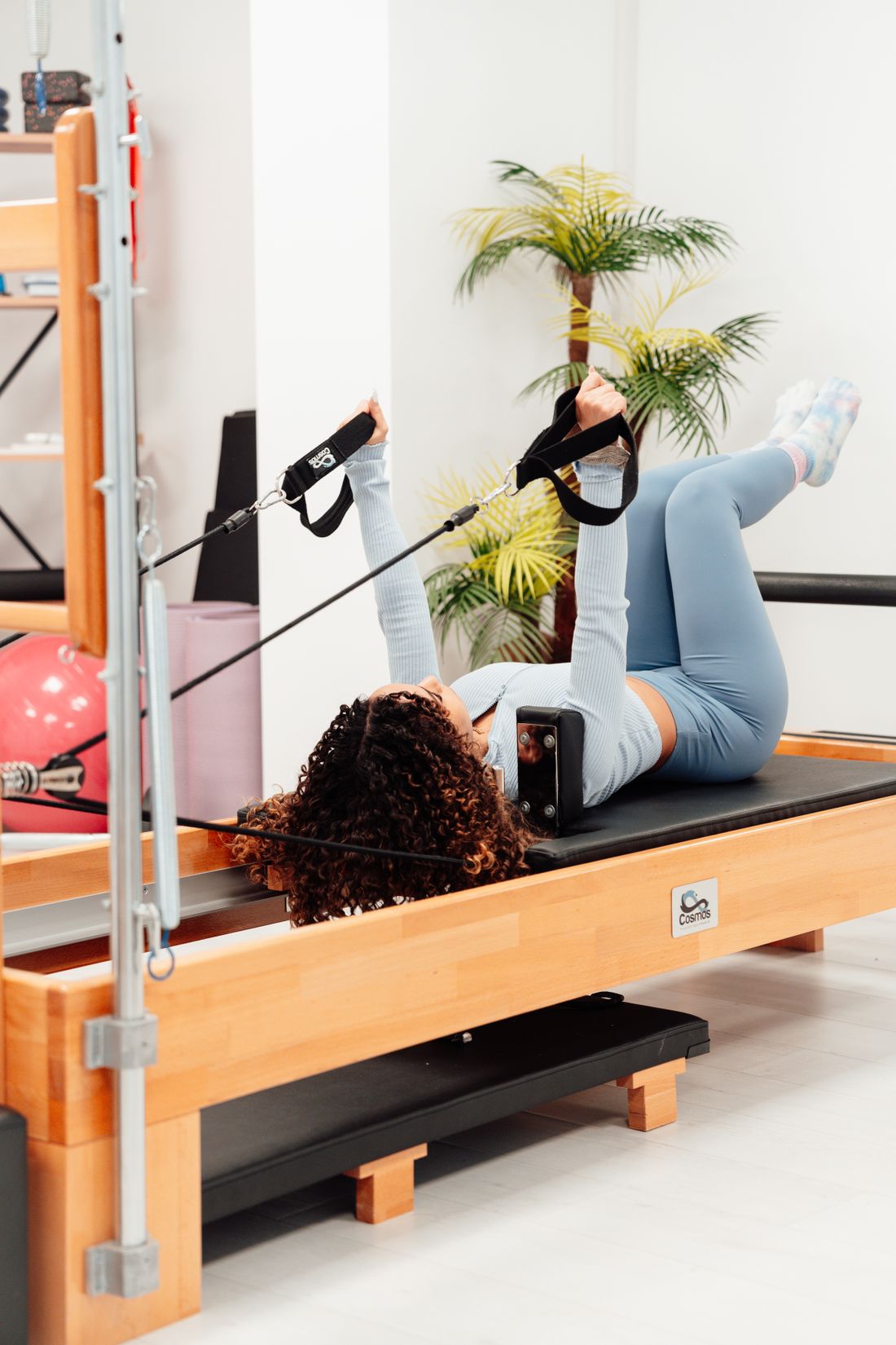 Mulher praticando pilates no reformer em posição ativa de exercício