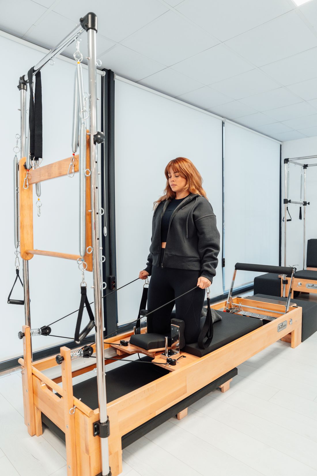 Estudio de pilates com aparelho: mulher em exercicio na torre de pilates
