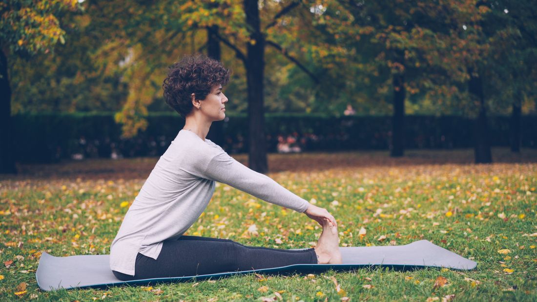 Saude e bem-estar da mulher: mulher praticando yoga em parque no outono